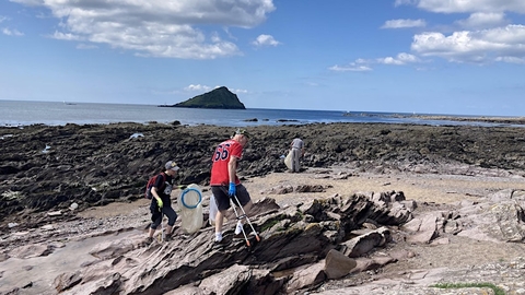 People with litter pickers cleaning a beach